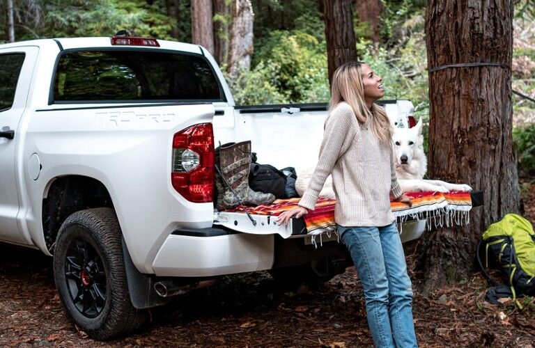 A woman relaxing by the tailgate of a white 2021 Toyota Tundra