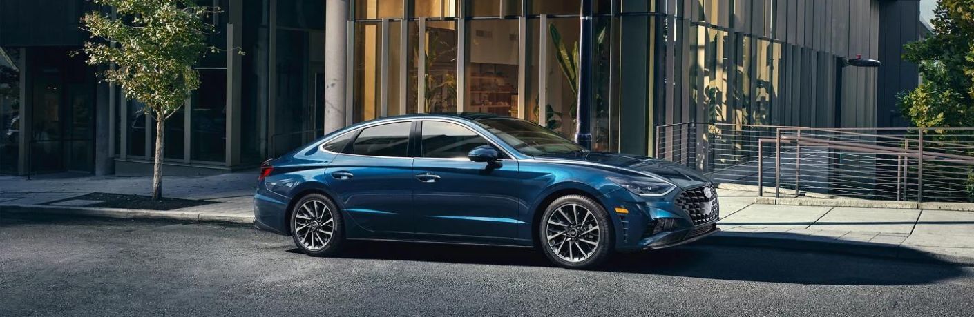 A blue Hyundai Sonata parked outside a glass building.