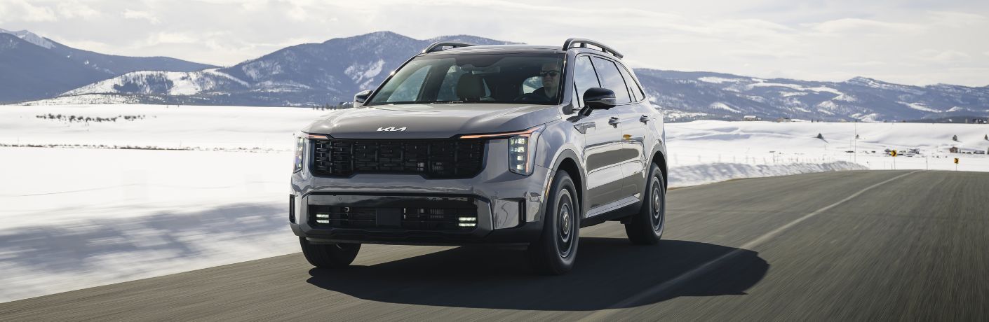 front quarter view of the 2025 Kia Sorento on a road near snowy mountains