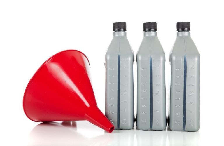 A red funnel with three quarts of motor oil on a white background