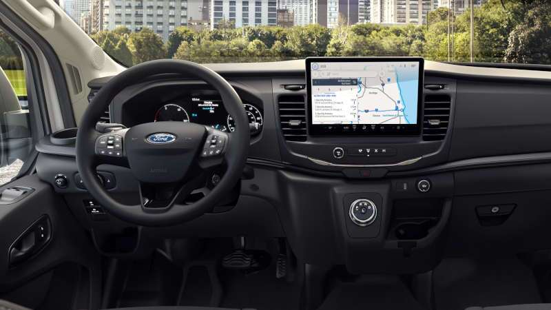 The cockpit, controls, and displays in the 2025 Ford E-Transit cargo van on a city street.
