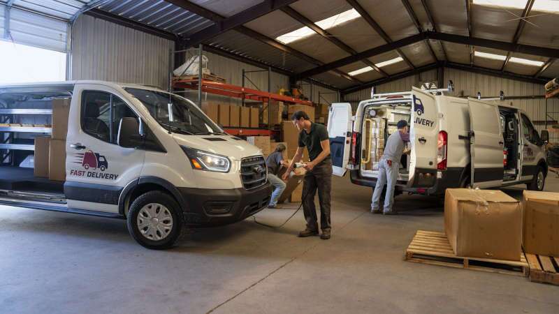 Workers in a warehouse loading and charging the 2026 Ford E-Transit Cargo Van near Atlanta