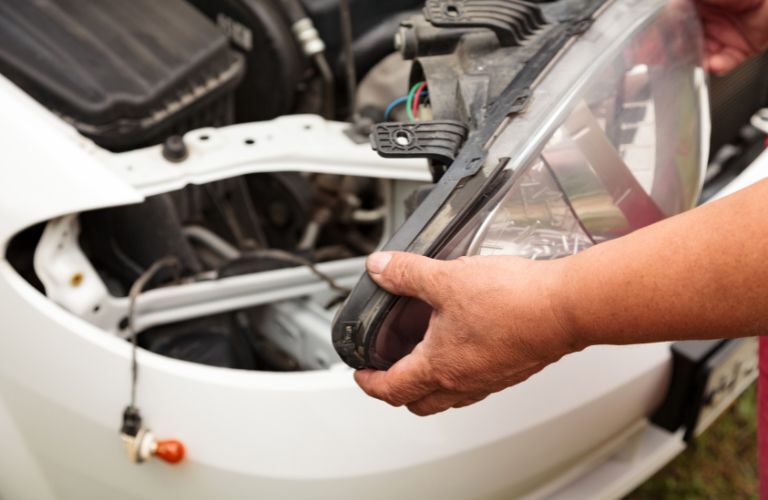technician fitting a headlight in a car