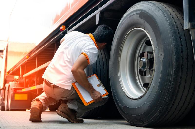 A man doing a pre-trip inspection on a heavy commercial truck.