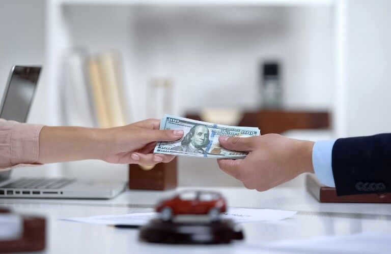 Person handing money to a car salesman