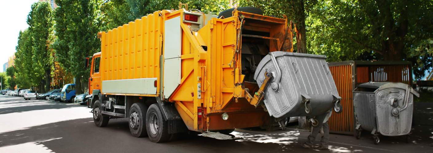 A rear-loader garbage truck picking up a load.