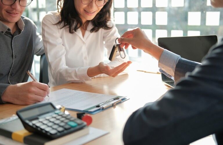 Car salesman giving customers car keys