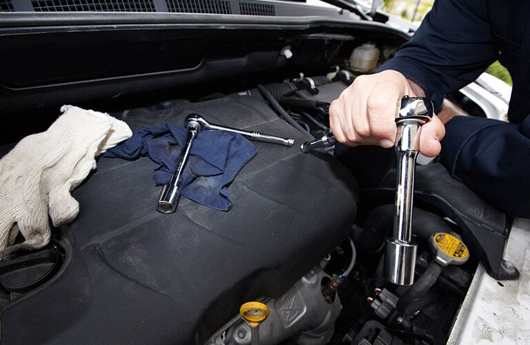 service technician working on engine with socket wrench