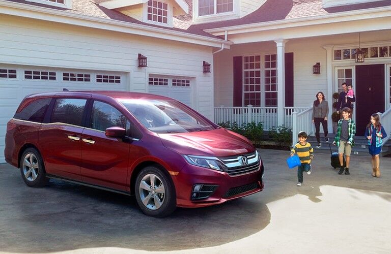 Front passenger angle of a red 2020 Honda Odyssey parked by a home