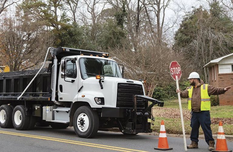 A man directing a used Freightliner 108SD on road