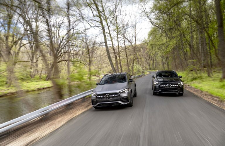 2021 MB GLA exterior front fascia of 2 models on wooded road