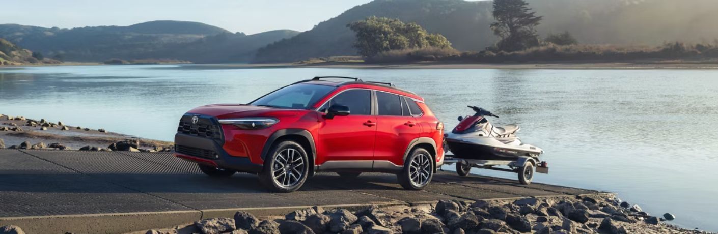 front quarter view of the 2026 Toyota Corolla Cross Hybrid towing a water bike near the lake