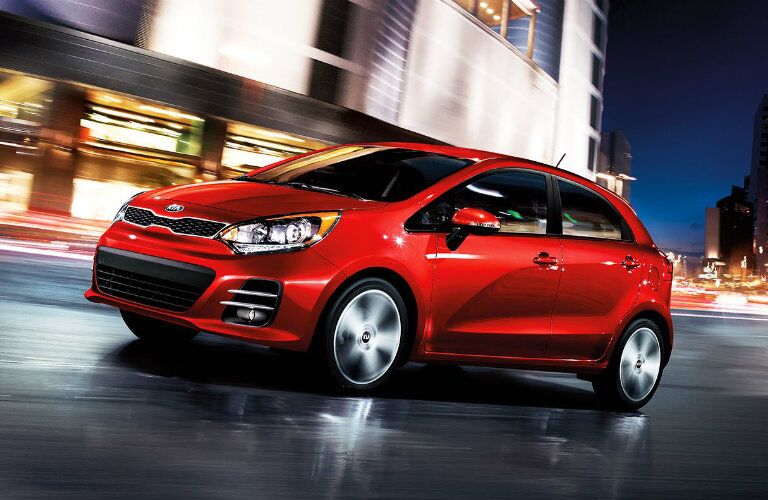 Front driver angle of a red 2016 Kia Rio driving down a road