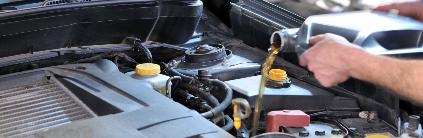 Mechanic pouring oil in the car