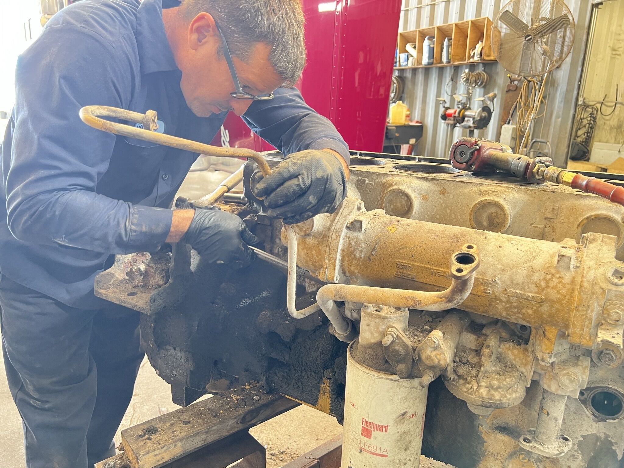 A mechanic working on a diesel engine with the valve covers off