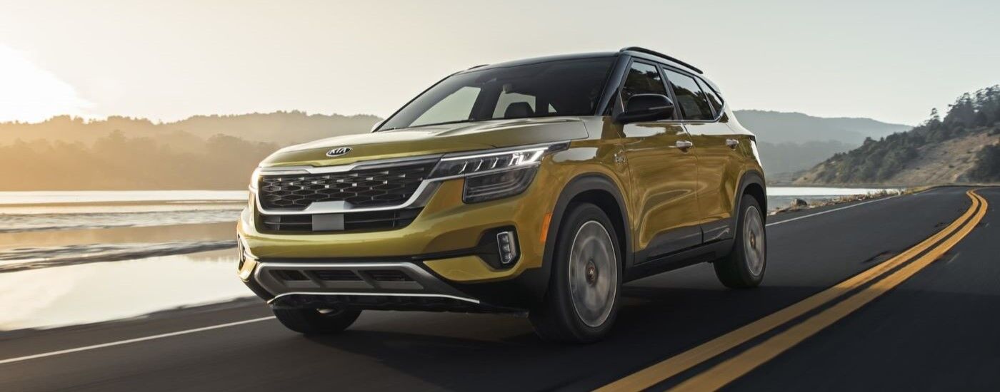 Yellow 2021 Kia Seltos driving next to a body of water.