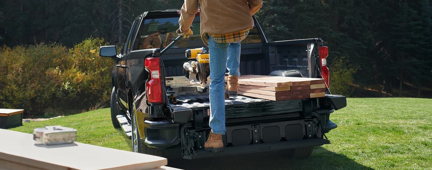 A black 2022 Chevy Silverado 1500 is full of wood and tools.