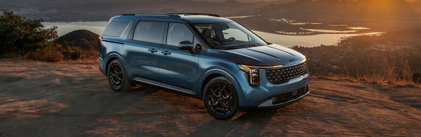 2026 Kia Carnival parked on a hill in front of a lake