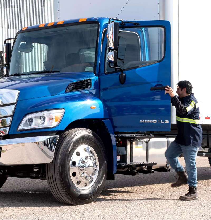 A driver getting into a large Hino delivery truck