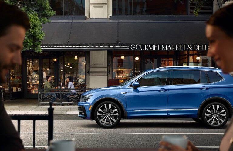 Driver angle of a blue 2020 Volkswagen Tiguan parked by a deli