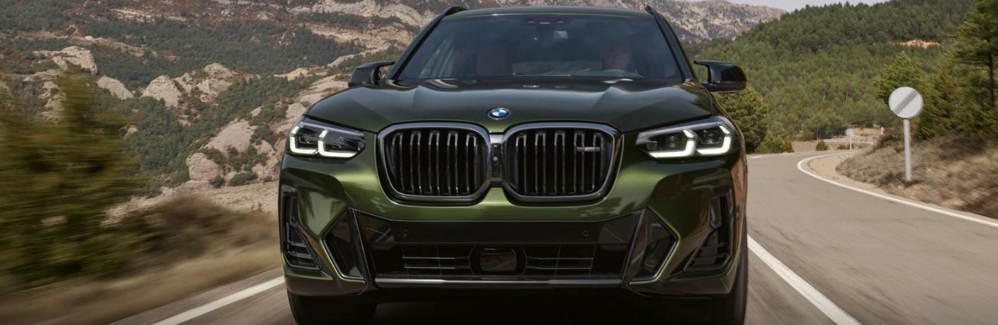 A green 2022 BMW X3 on a smooth countryside road