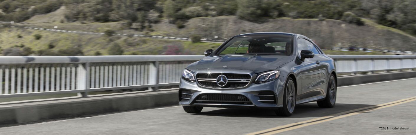 2020 MB CLS Coupe exterior front fascia and driver side going fast on blurred bridge with trees