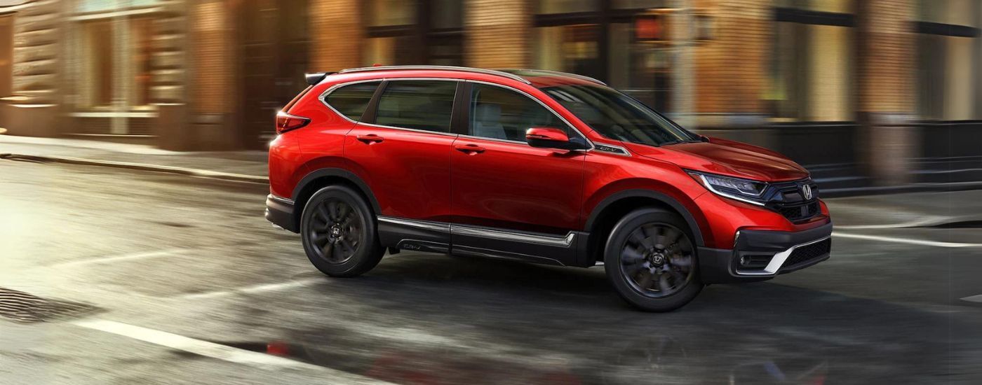 Red 2021 Honda CR-V driving through a city intersection.