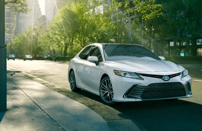2021 Toyota Camry white hybrid parked near green trees