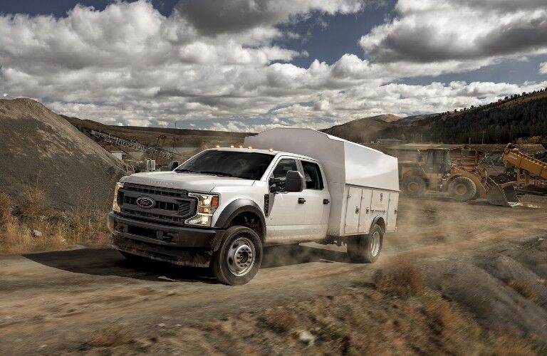 Front driver angle of a white 2020 Ford Super Duty Chassis Cab leaving a construction site