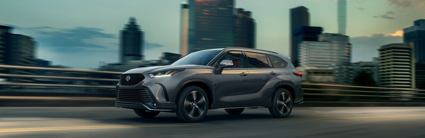 2021 Toyota Highlander driving on bridge through city dusk