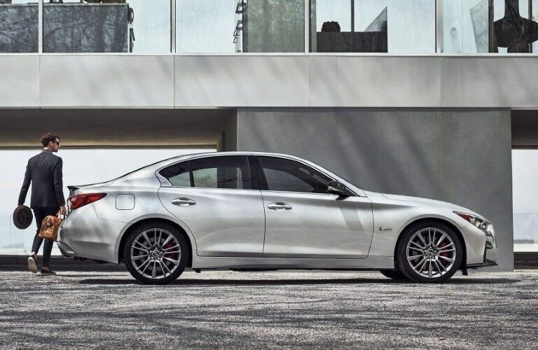 Passenger angle of a white 2020 INFINITI Q50 with a man walking around it