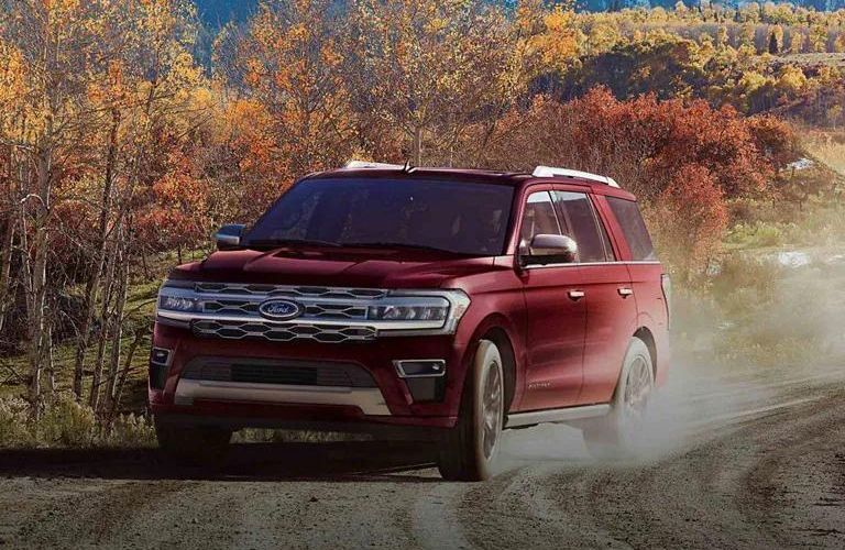 One red color 2022 Ford Expedition is running on the road surrounded by trees.