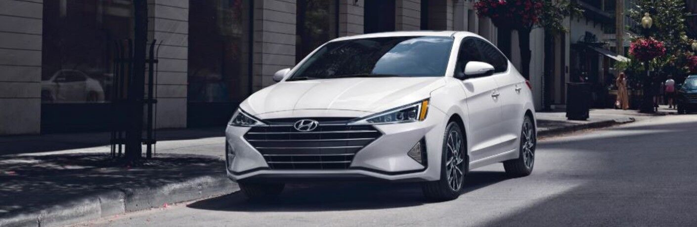 Front side view of the white Hyundai Elantra parked beside the road.