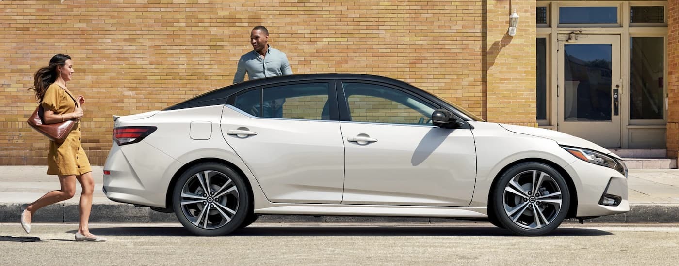Side of a white 2023 Nissan Sentra parked near a brick wall