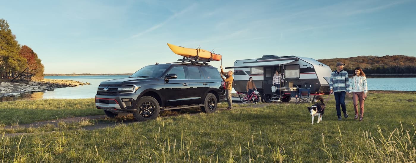 Black 2023 Ford Expedition parked at a campsite near a lake