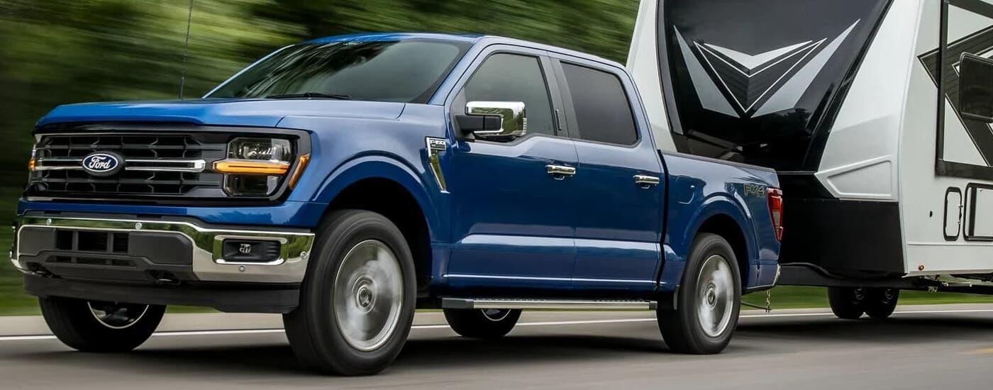 Blue 2024 Ford F-150 towing a camper