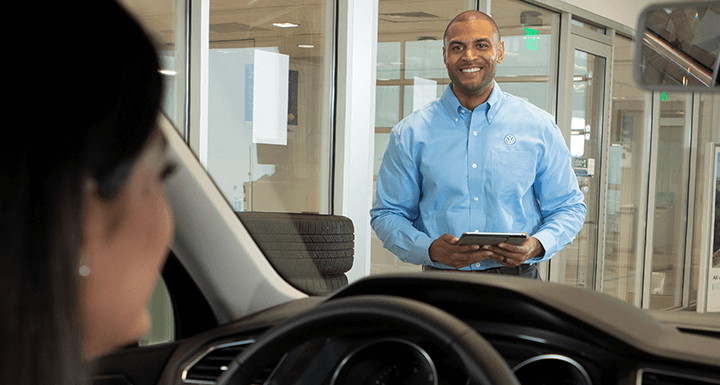 Volkswagen mechanic smiling next to open car hood