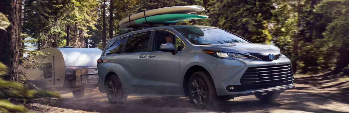 A 2024 Toyota Sienna carrying two surfboards and hauling a trailer