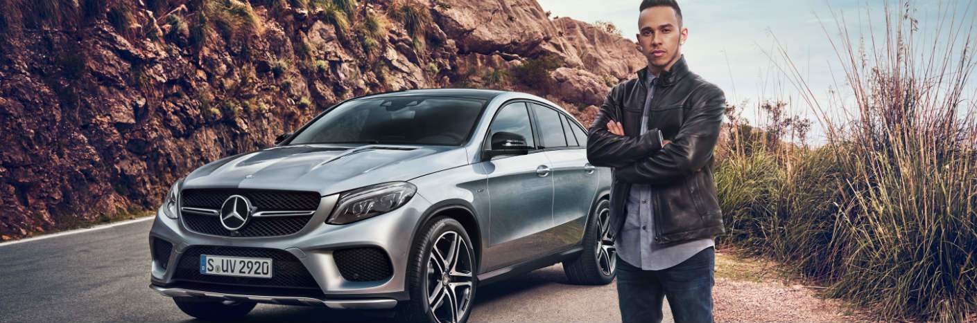 man standing next to silver Mercedes-Benz sedan