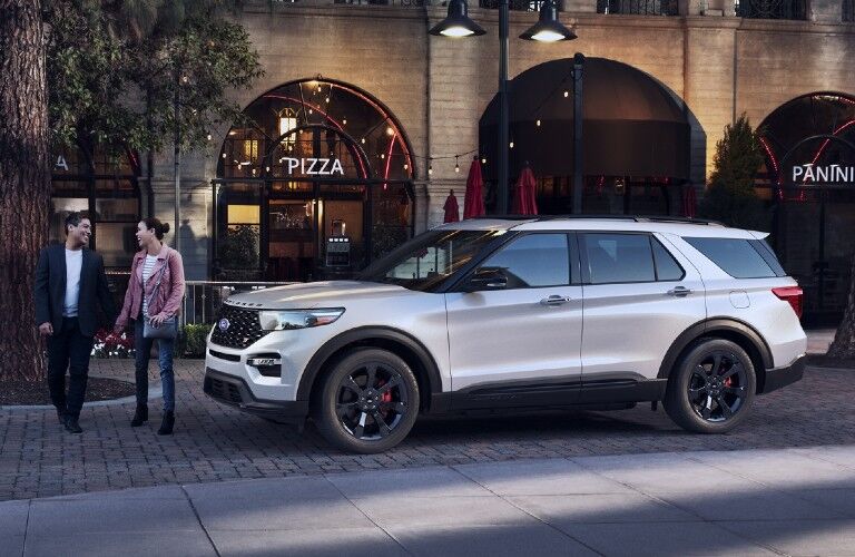 Driver angle of a white 2020 Ford Explorer with a couple walking in front of it
