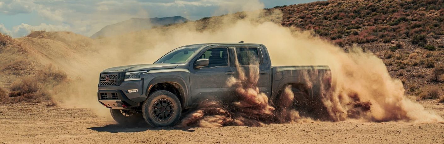 Side view of a 2022 Nissan Frontier driving through desert