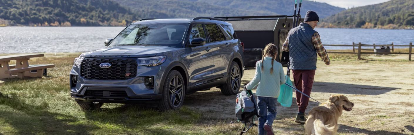Man with his daughter and dog walking towards 2025 Ford Explorer