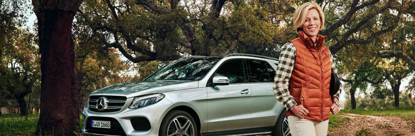 woman in a vest standing next to a Mercedes-Benz SUV