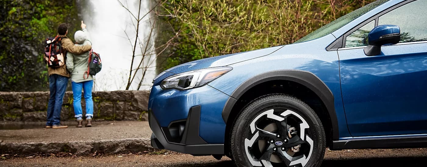 A blue 2023 Subaru Crosstrek Limited parked near a waterfall.