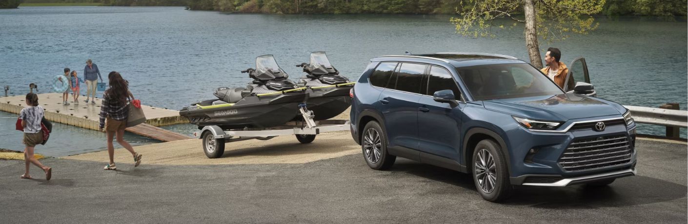 front quarter view of the 2025 Toyota Grand Highlander with a family around it enjoying near the lake