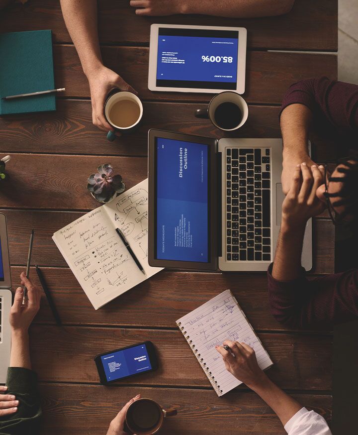 arial view of people at table with computers and notebooks