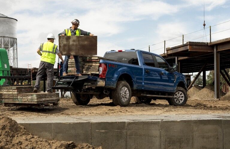 Workers loading boxes in bed of blue 2020 Ford Super Duty F-250 pickup