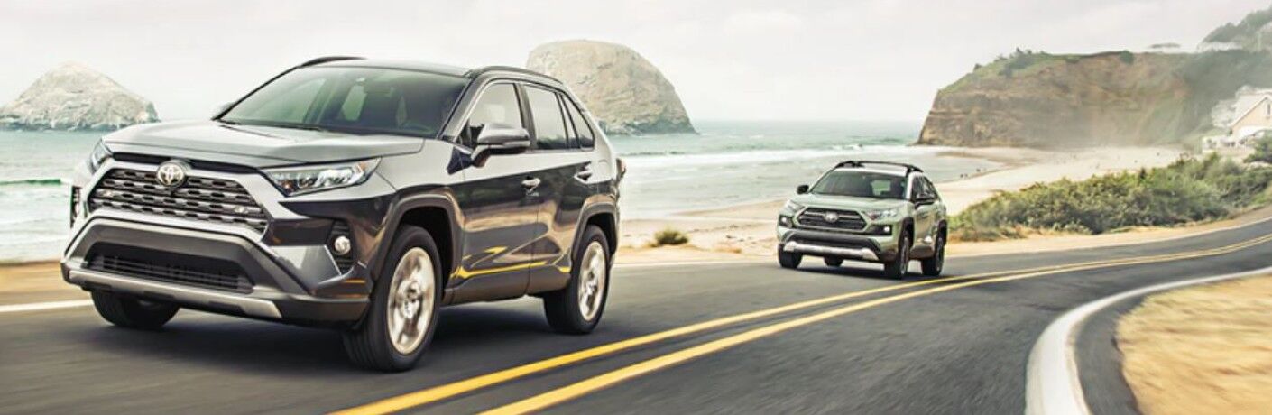 Two 2021 Toyota RAV4 models driving down a beachside road