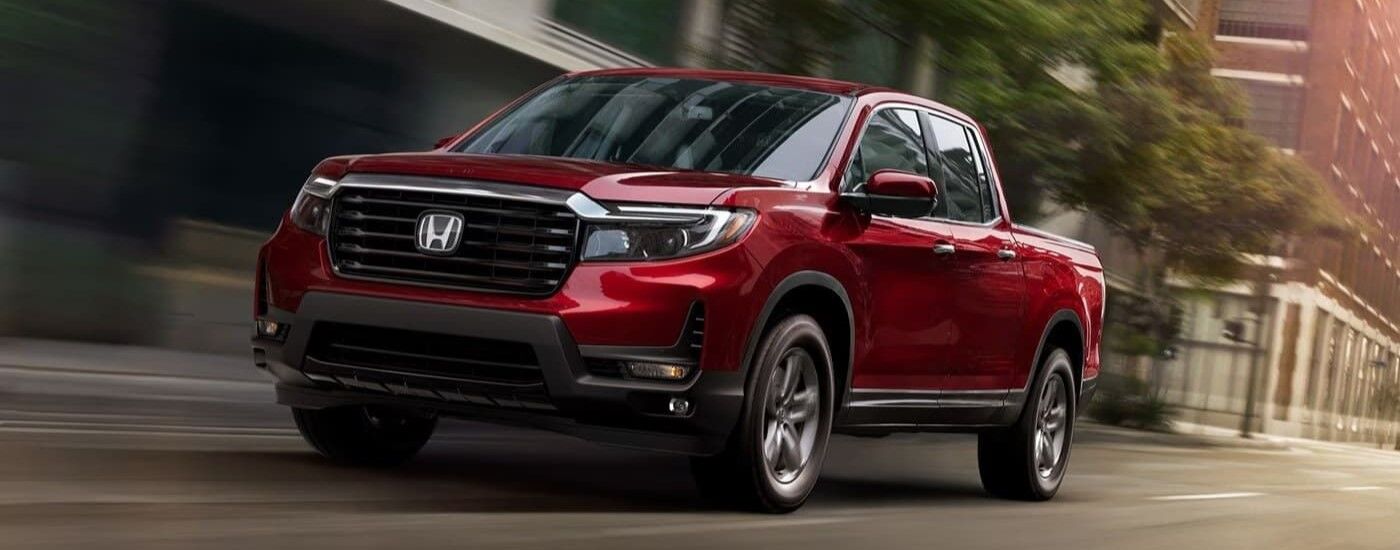 Red 2024 Honda Ridgeline driving on a city street