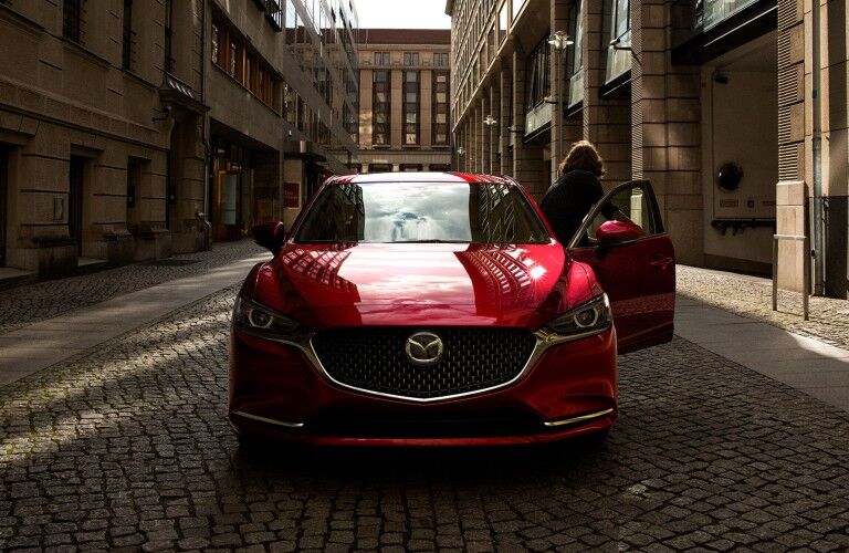 Front angle of a red 2021 Mazda6 with a woman exiting the vehicle